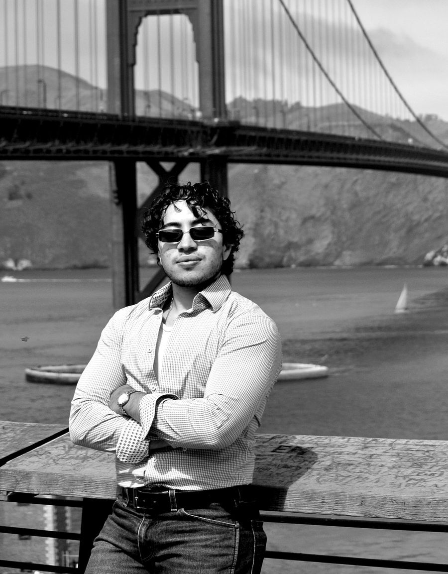 Rodrigo Zepeda in a checked shirt, arms crossed, in front of the Golden Gate Bridge
